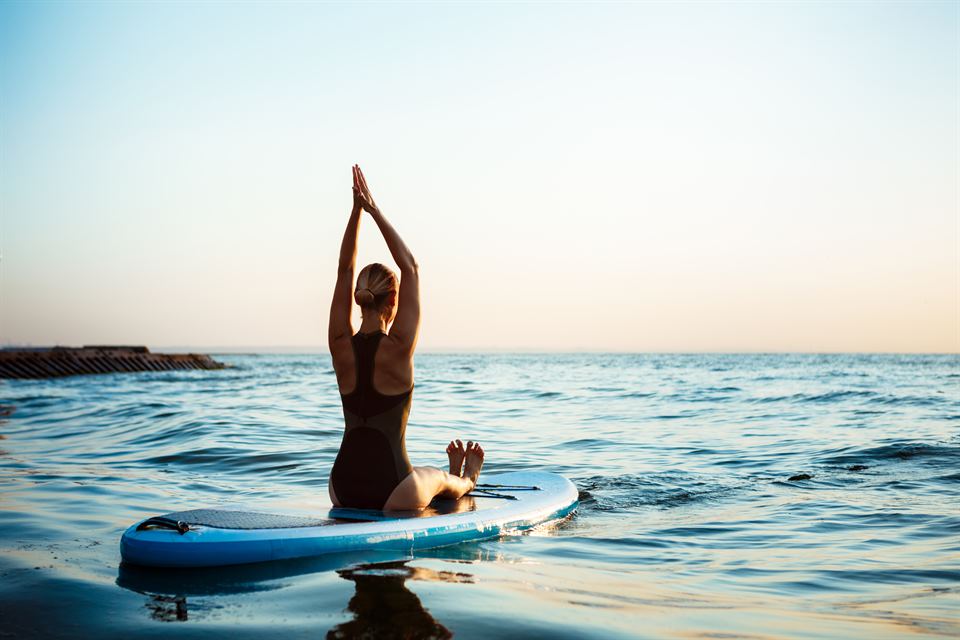 postura de yoga en tabla de paddle surf